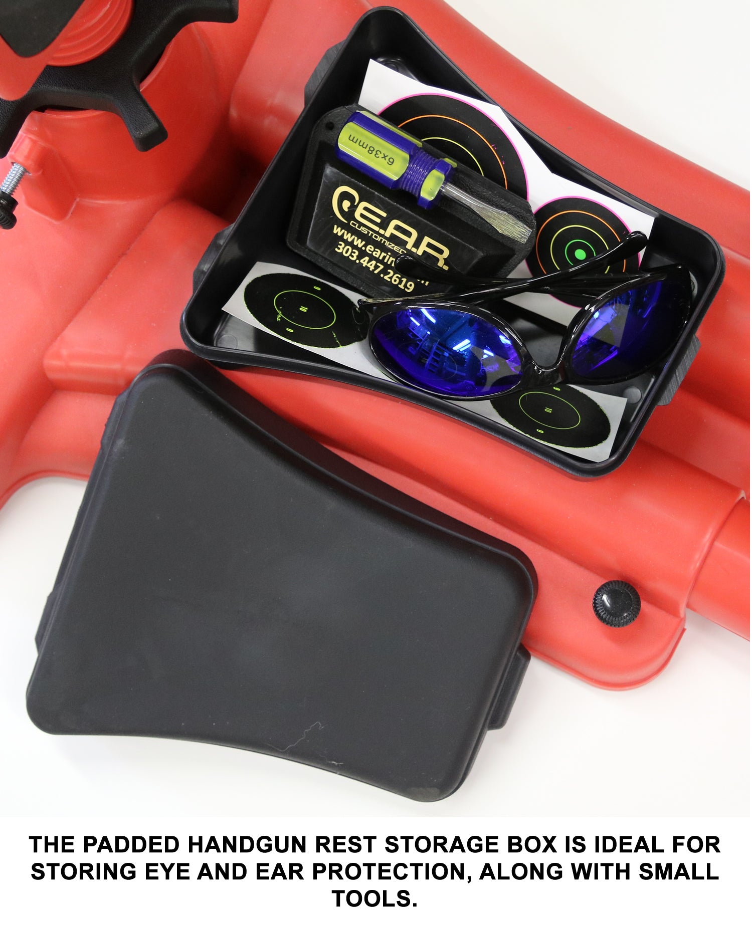 Padded handgun rest storage box with eye and ear protection, and small tools on a white background.